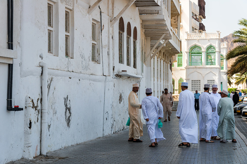 Muscat, Oman - March, 17. 2019 - Al Bahri Road im Muscat - Oman with view to historic white buildings and parking modern cars. Local people walking in the street.