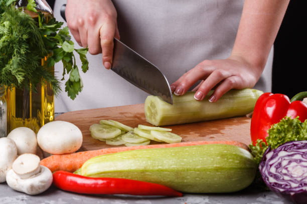 istock young woman in a gray apron cuts a cucumber 1144785950