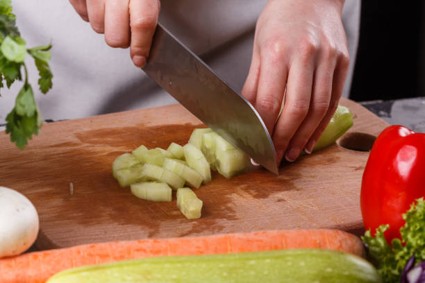 istock young woman in a gray apron cuts a cucumber 1144785999