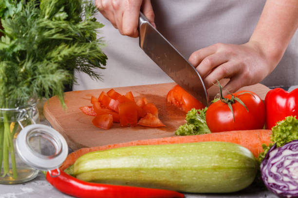 istock young woman slicing a tomato in a gray apron 1144789621