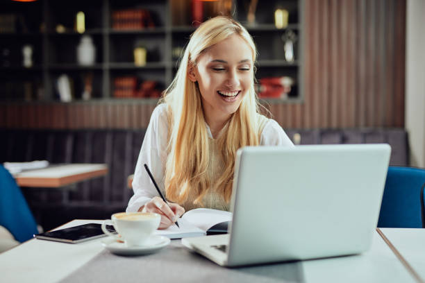 istock Busiensswoman writing notes and looking at laptop in cafe. 1144791805