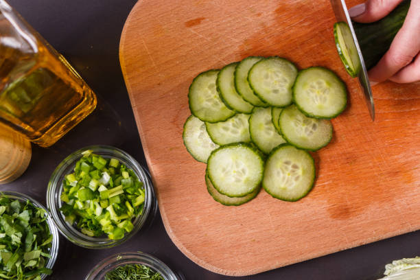 istock young woman in a gray apron cuts a cucumber 1144794775