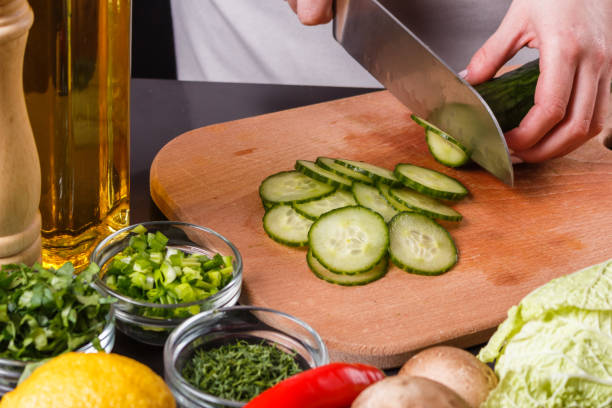 istock young woman in a gray apron cuts a cucumber 1144794834