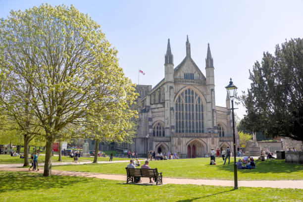 los turistas y visitantes sentados alrededor de la famosa catedral de winchester en el cálido domingo de pascua sunshine a finales de abril - uk cathedral cemetery day fotografías e imágenes de stock