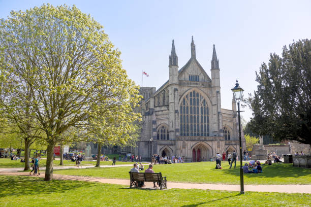 Tourists and visitors sitting around the famous Winchester Cathedral in the warm Easter Sunday Sunshine in late April stock photo