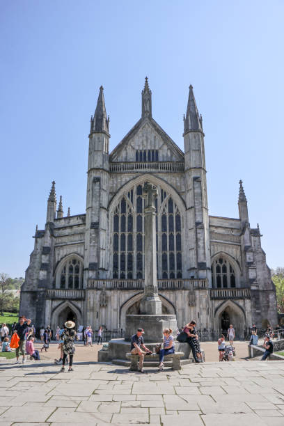 tourists and visitors sitting around the famous winchester cathedral in the warm easter sunday sunshine in late april - uk cathedral cemetery day imagens e fotografias de stock