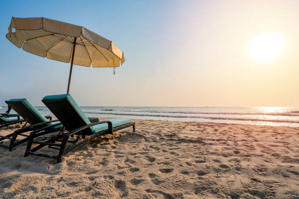 istock Sun umbrellas and chairs on tropical beach with sunset 1144801632