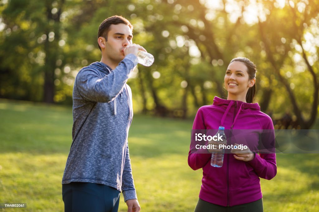 Exercising in park. Young couple exercising in park. They are drinking water. 20-29 Years Stock Photo