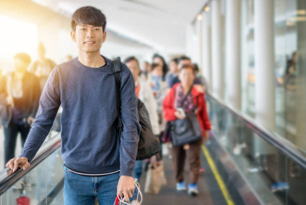 pria muda asia bepergian dengan transportasi umum dan menunggu kereta di bandara - bandara korea potret stok, foto, & gambar bebas royalti