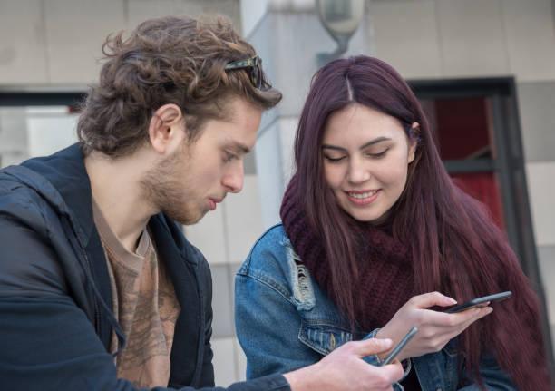 istock couple of student sitting watching phone 1144803707