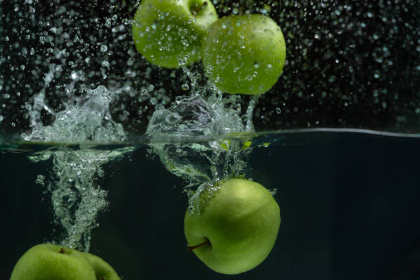 istock Fresh green apple splashing into clear water on black background 1144805810