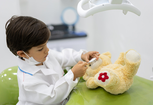 Portrait of a little boy at the dentistâs office playing with his teddy bear â healthcare and medicine concepts