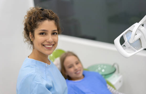 glücklicher zahnarzt prüft eine girlâs-zähne - dental equipment chair dentist office dentists chair stock-fotos und bilder
