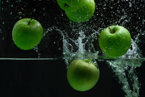 Fresh green apple splashing into clear water on black background