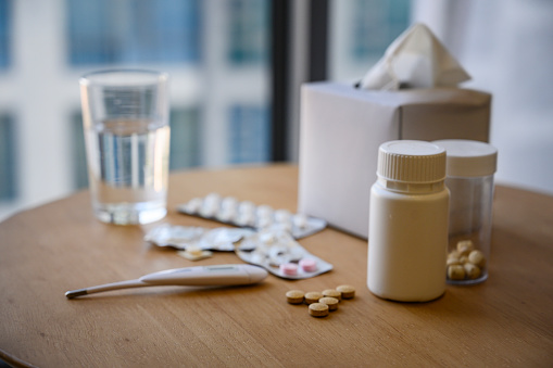 facial tissue , medicine , pill bottle and tablet with glass of water on the table