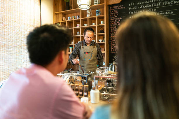 istock Mature man making coffee for couple in coffee shop 1144812149
