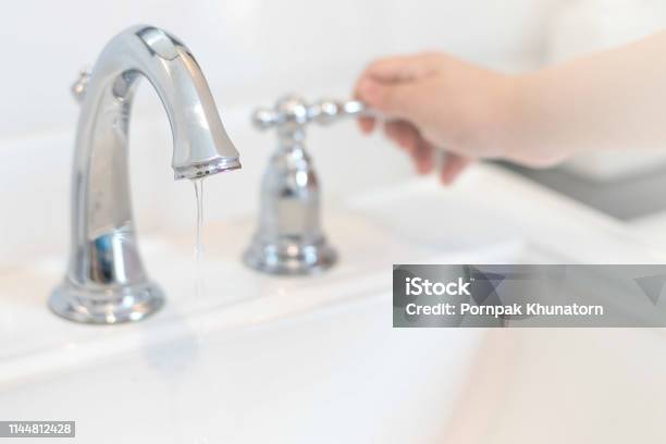 Save The Water Concepthand Closing Valve On Sink In Bathroom Water Dripping To Stop Running As Hand Turn Off The Faucetdetectaleak Week Stock Photo - Download Image Now