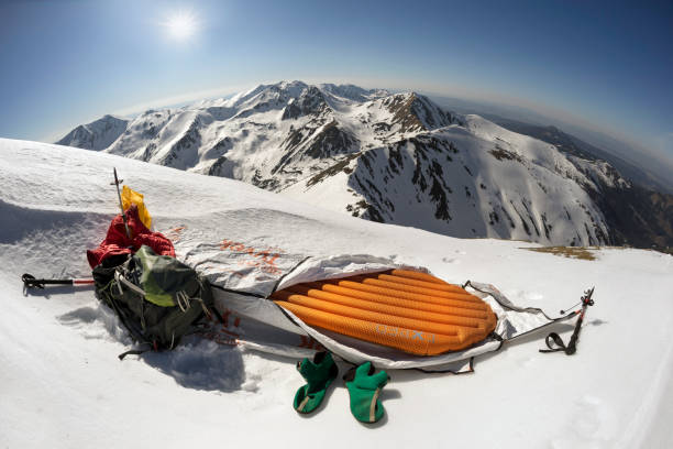Poland, Zakopane, April 19, 2019: mountaineer is going to spend the night on the top of the mountain in the Tatras in a light bivouac bag Tyvek on an inflatable mattress. The company Exped produces high-quality equipment