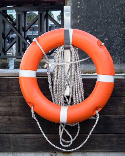 istock Orange life preserver or life buoy with coiled rope on a hook on dock 1144815221