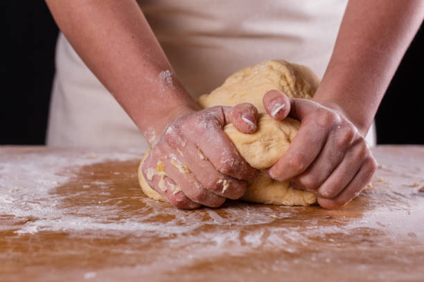 istock young woman in apron kneading dough on board 1144820713