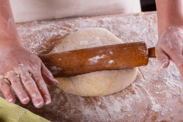 istock young woman in apron kneading dough on board 1144820751