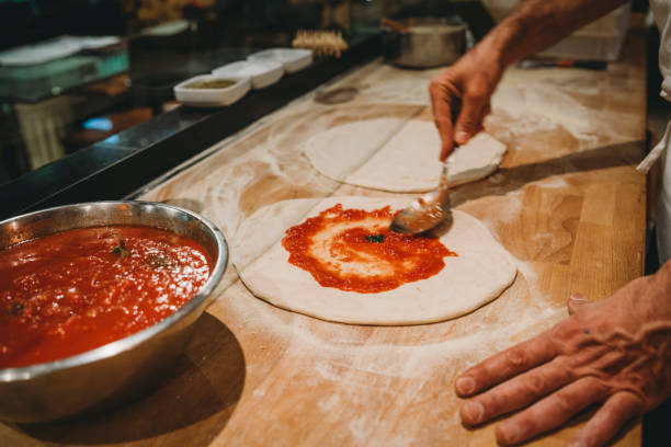 pizzaiolo che prepara una pizza al ristorante - impastare foto e immagini stock