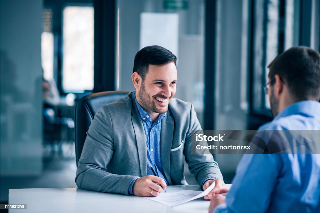 Hübsches männliches Kundenunterzeichnungsdokument auf einem Treffen mit Immobilienmaklern. - Lizenzfrei Bankdirektor Stock-Foto