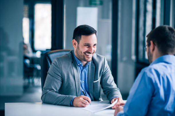 Handsome male client signing document on a meeting with real estate agent. Handsome male client signing document on a meeting with real estate agent. bank manager stock pictures, royalty-free photos & images