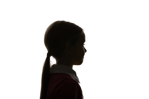 Silhouette of child with ponytail looking away isolated on white