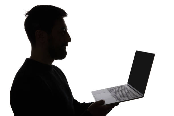 istock Silhouette of man holding laptop with blank screen isolated on white 1144824634