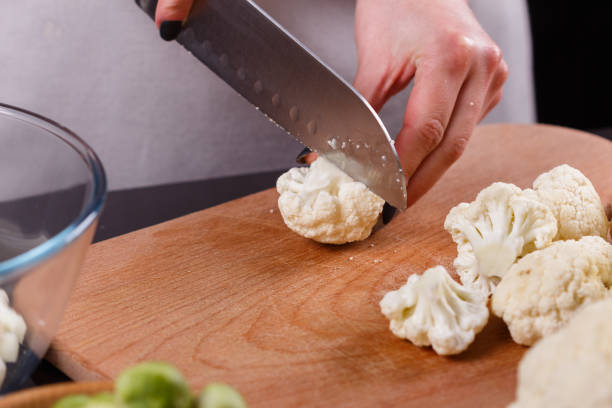 istock young woman in a gray aprons cuts cauliflower broccoli 1144826458