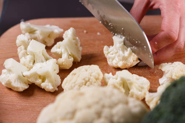 istock young woman in a gray aprons cuts cauliflower broccoli 1144826510