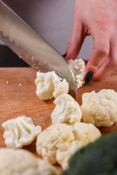 istock young woman in a gray aprons cuts cauliflower broccoli 1144826557