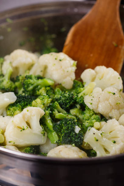 istock young woman in a gray apron roasts cauliflower broccoli 1144826569