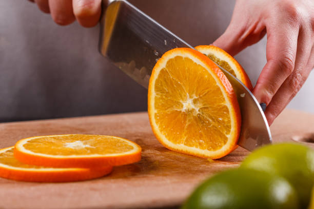 istock young woman in a gray aprons cuts an orange 1144830901