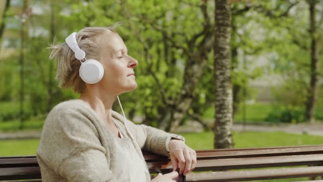 Woman relaxing and listening to music in the park