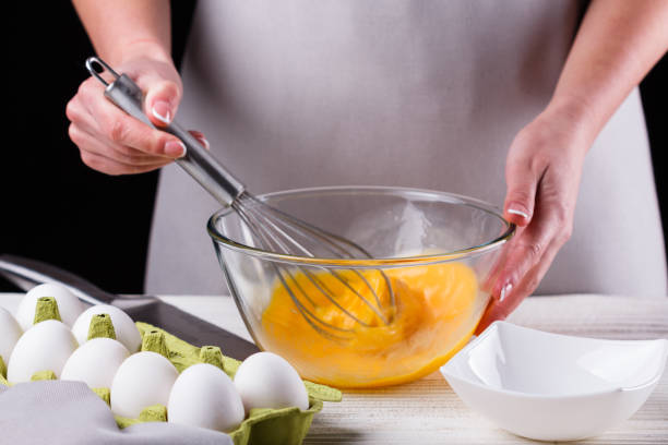 young woman in a gray aprons breaks the eggs - equipment egg beater household equipment kitchen utensil imagens e fotografias de stock