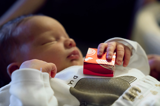 Newborn baby holding gift box while sleeping