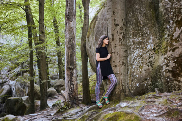 istock Young attractive girl stand in forest and lean on a tree 1144840129