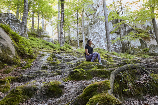 istock Young attractive girl sit on the big rock in forest 1144840136