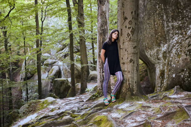 istock Young attractive girl stand in forest and lean on a tree 1144840141