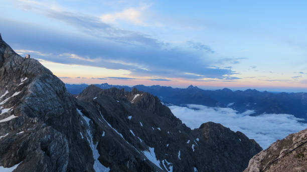 vue tôt le matin du sommet de montagne avec des formations rocheuses et une couverture nuageuse - mountain rock sun european alps photos et images de collection
