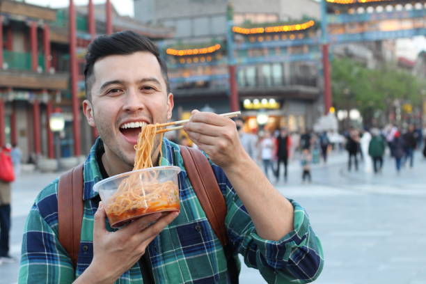 istock Man eating noodles outdoors in Asia 1144840501