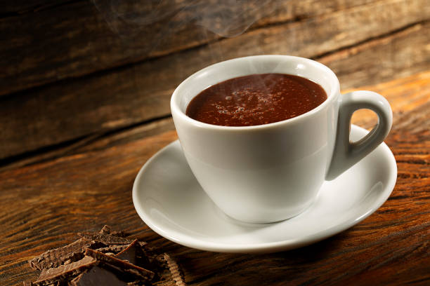 Hot Chocolate cup on wooden background with piece of chocolate stock photo