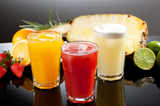 Grape juice, strawberry juice, passion fruit juice on wooden background and with reflection. Grape, strawberry and mint.