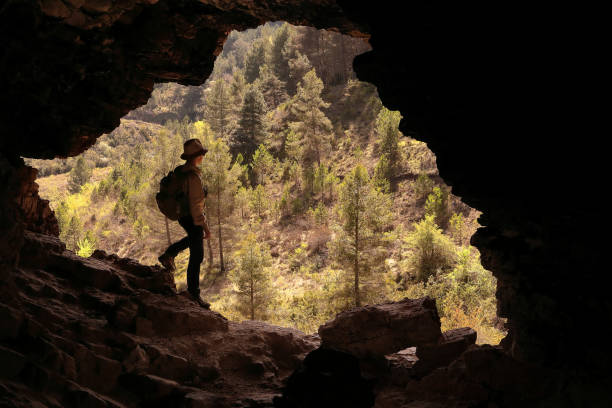 istock ADVENTURER MOUNTAINEER MAN  WITH HAT AND BACKPACK LOOKING FROM A CAVE A VALLEY WITH BEAUTIFUL GREEN TREES 1144842898