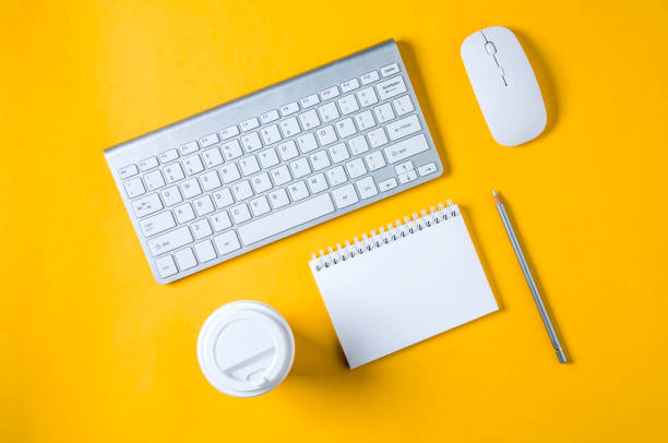 istock White keyboard, mouse and Notepad on yellow background. Flat lay and top view 1144845077