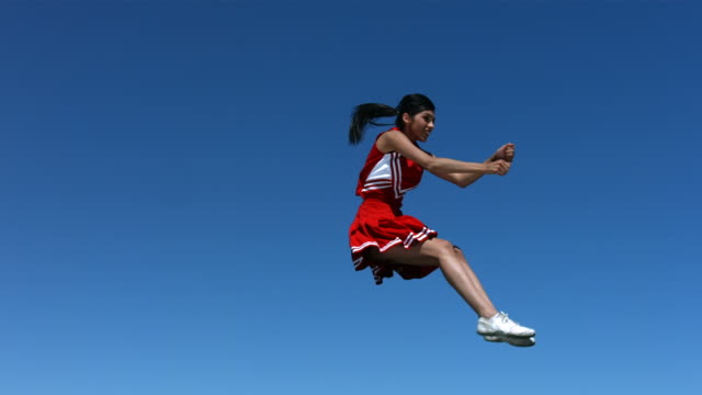 Cheerleader performs aerial stunt , slow motion