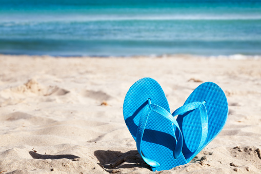 Blue flip flops on sand beach. Summer vacation concept