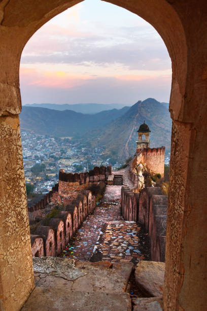 Ancient long wall with towers around Amber Fort through the arch of tower walls at morning. Rajasthan. India stock photo